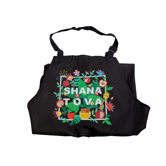 A black apron with a colorful floral border and the words 'SHANA TOVA' printed in the center, shown against a plain white background.