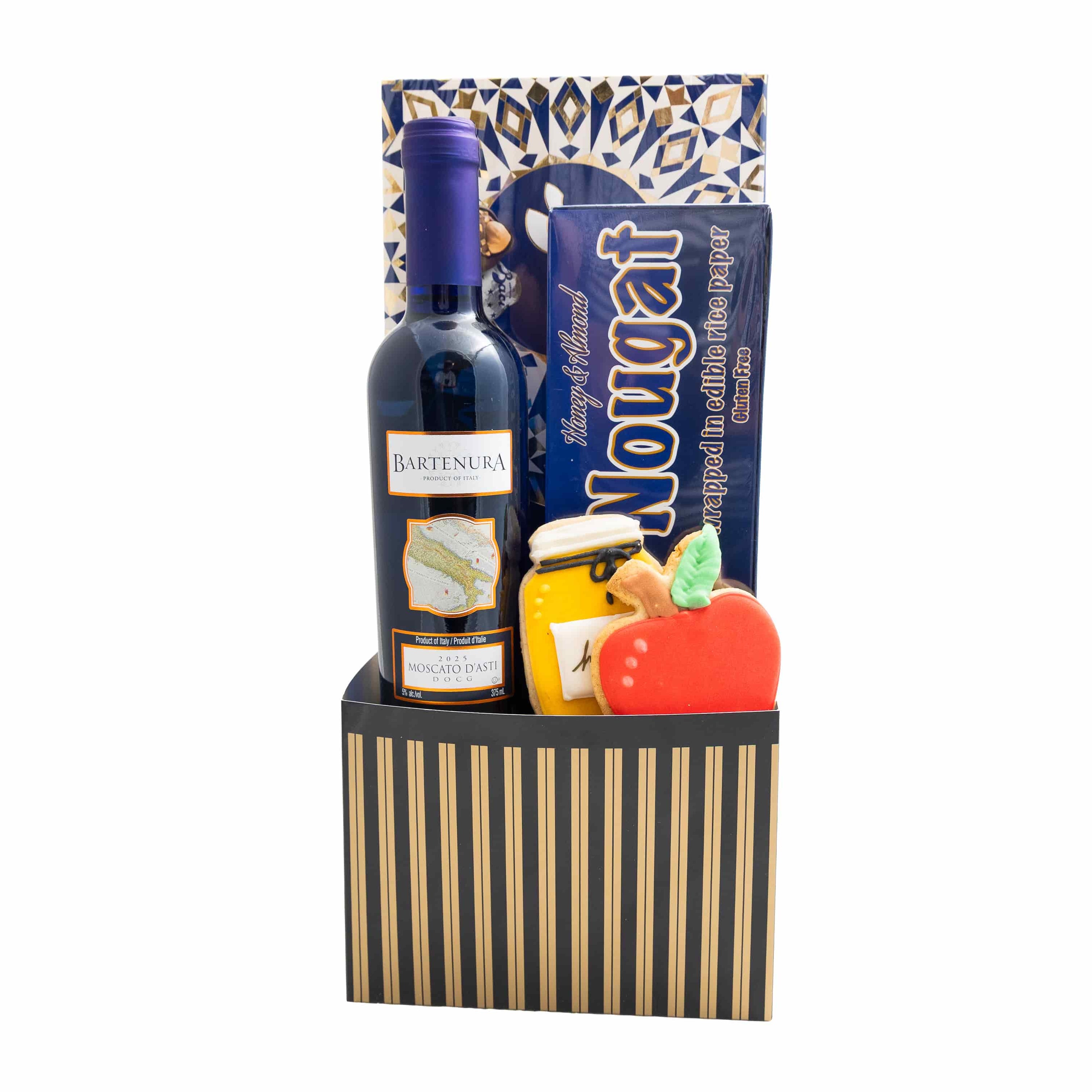 A gourmet gift basket featuring a bottle of wine, a bag of chocolate, a box of nougat, and a striped black and gold basket, isolated on a white background.