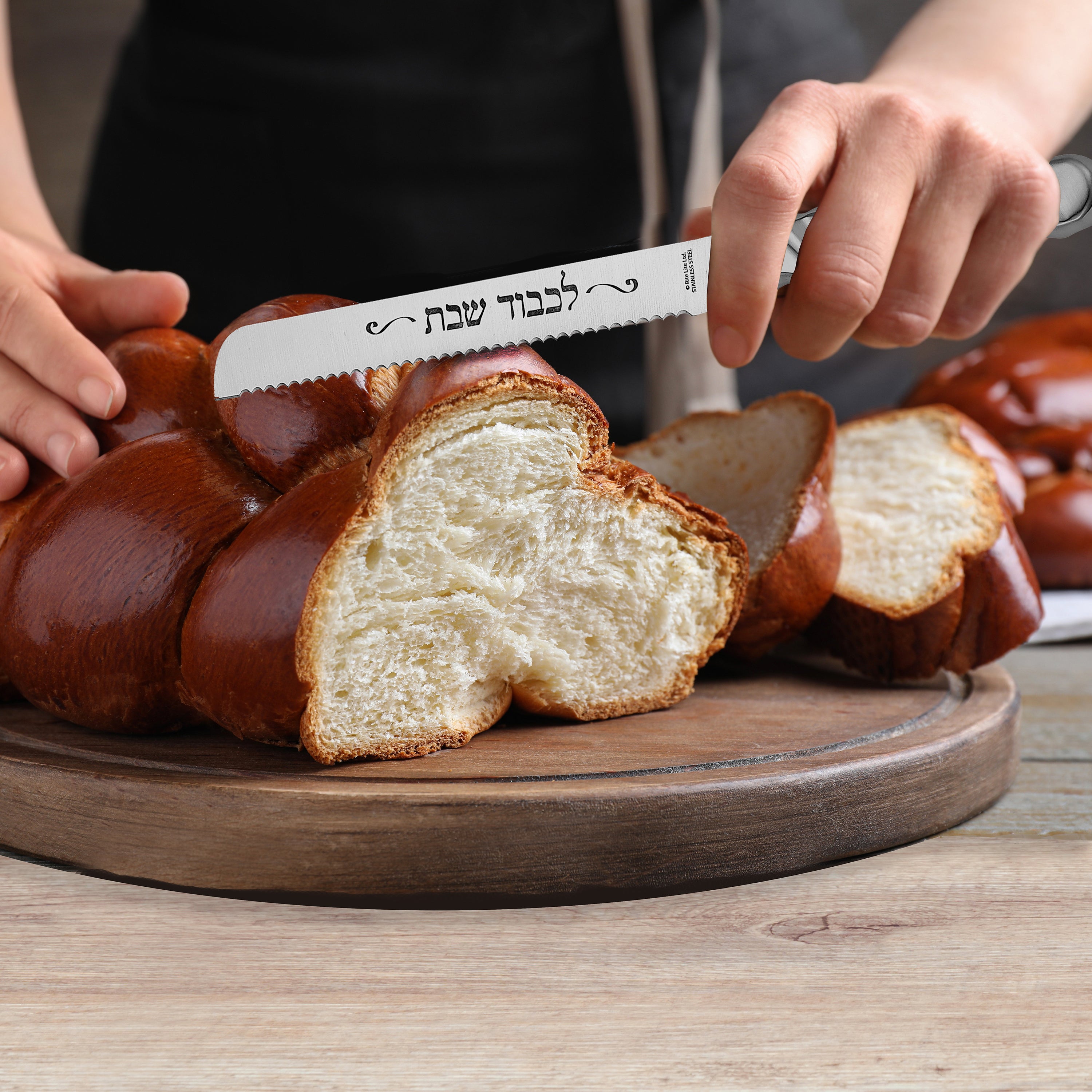 Person slicing a loaf of bread with a serrated knife on a wooden cutting board.