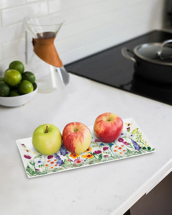 Three apples on a floral-patterned tray in a kitchen setting