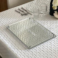 Clear glass tray on a textured white tablecloth with cutlery and glasses.
