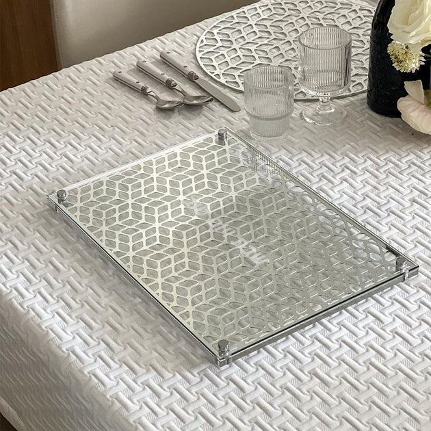 Clear glass tray on a textured white tablecloth with cutlery and glasses.