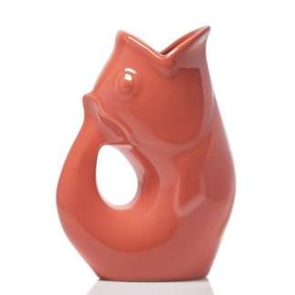 A glossy ceramic fish-shaped pitcher in a warm terracotta or coral-orange color, set against a plain white background.
