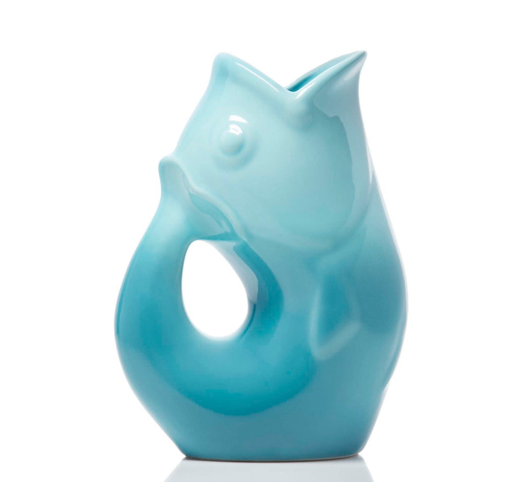 A glossy light blue ceramic fish-shaped pitcher with a small opening at the top, photographed on a clean white background.
