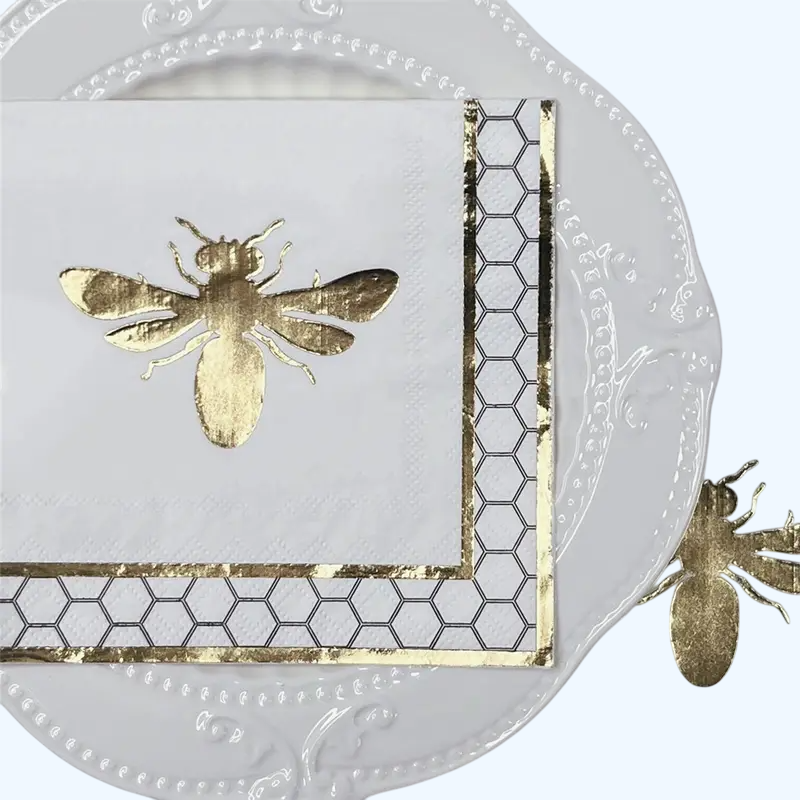 Decorative napkin with gold bee and honeycomb design on a white background