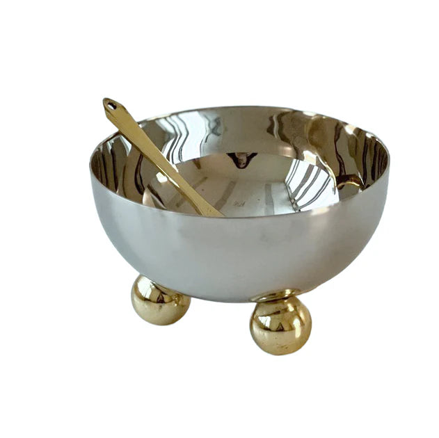 Silver bowl with gold accents and a gold spoon on a white background